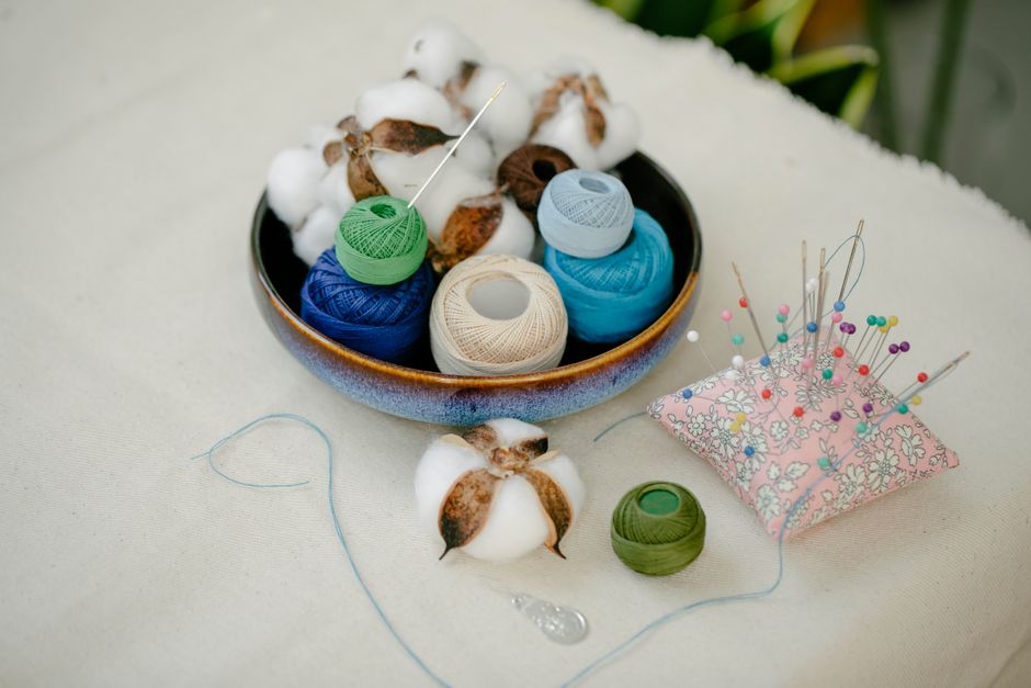 A vibrant arrangement of sewing threads, needles, and cotton displayed creatively on a table.