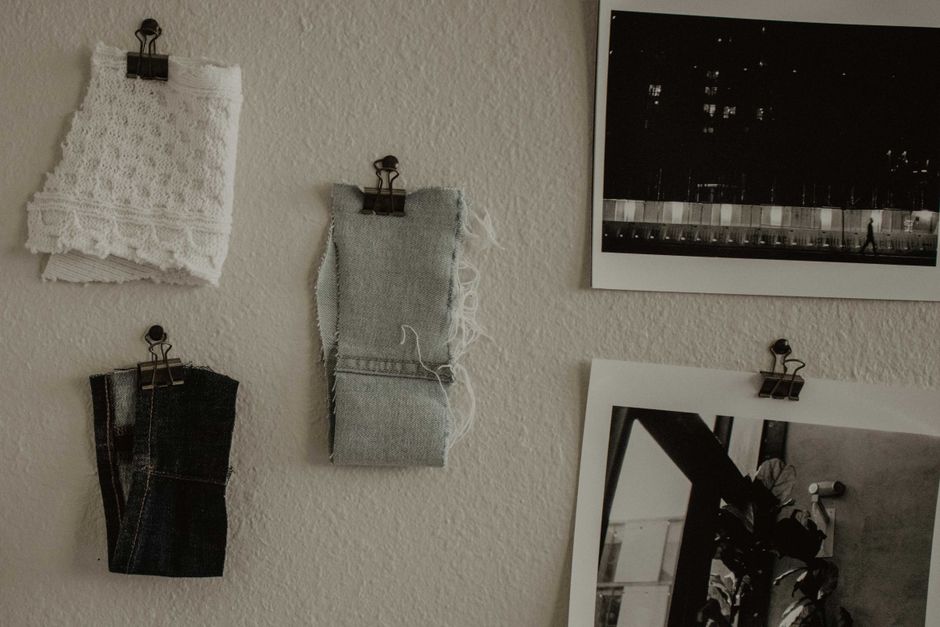 Stylish arrangement of fabric swatches and monochrome photos on a textured white wall.